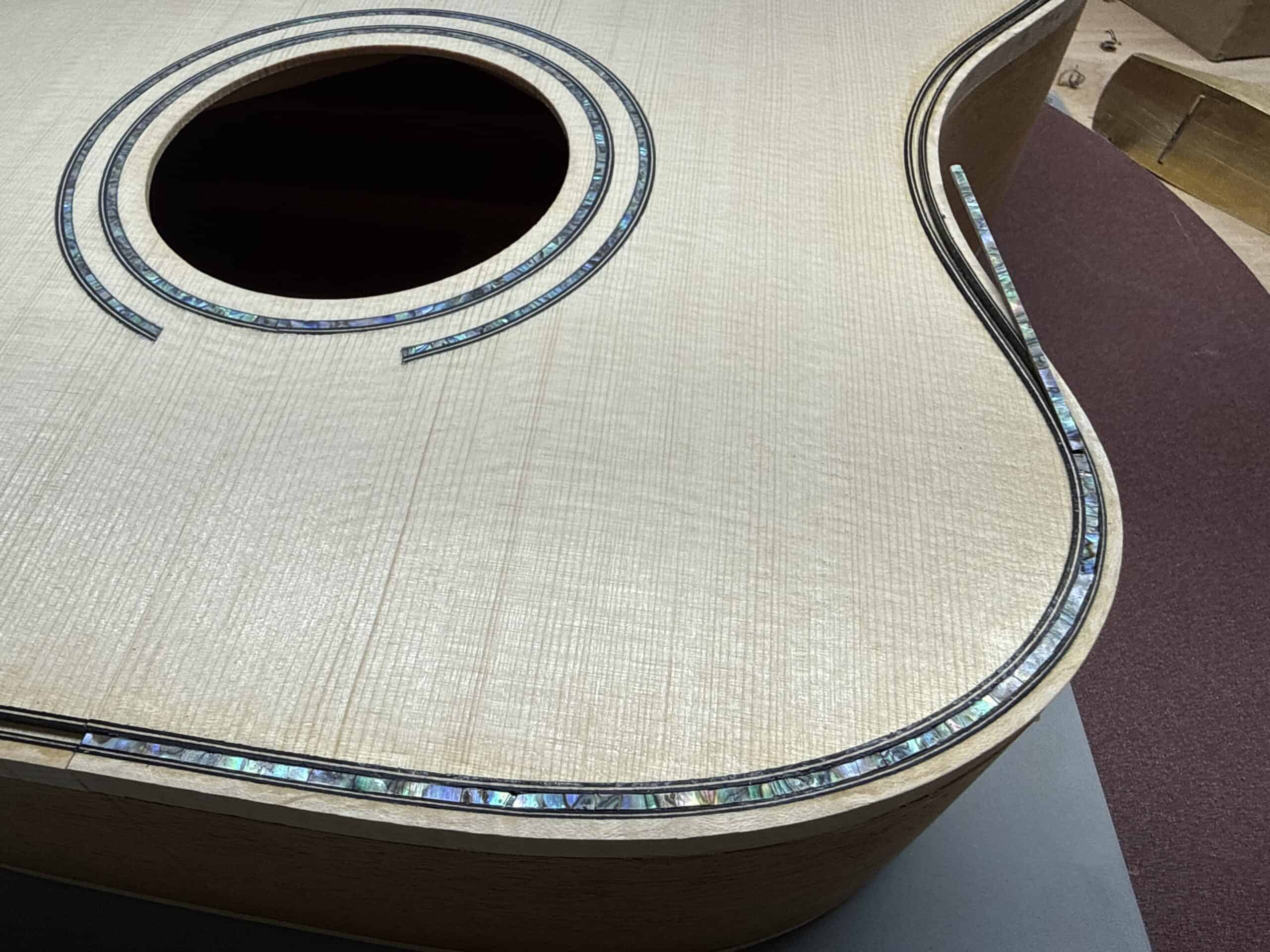 Close-up of an acoustic guitar body showcasing intricate inlay design and soundhole.