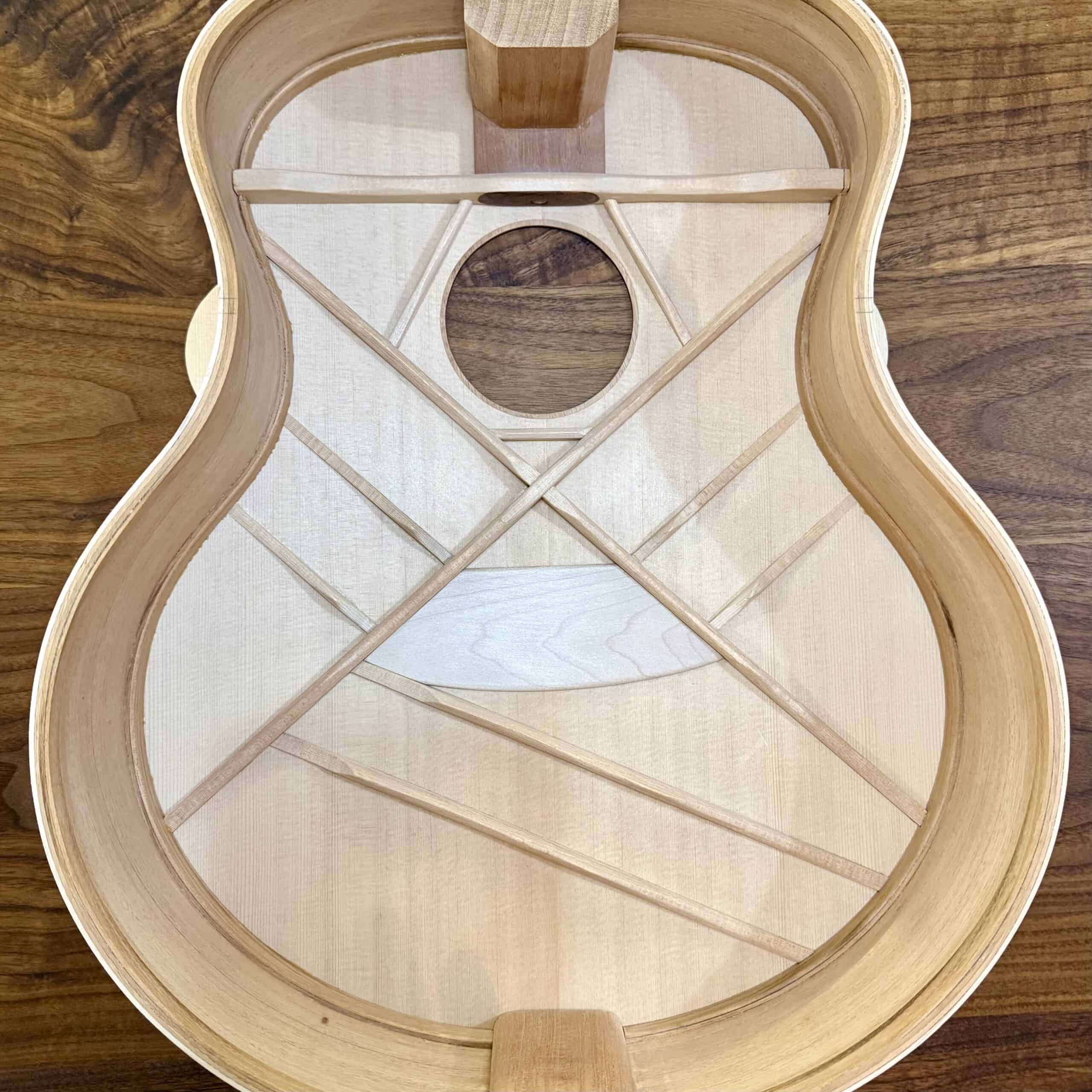 Unfinished wooden guitar body frame showcasing internal bracing and construction details.